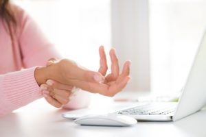 Woman with wrist pain while typing on the computer