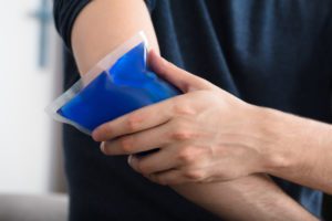 Man holding an ice gel pack on his elbow injury