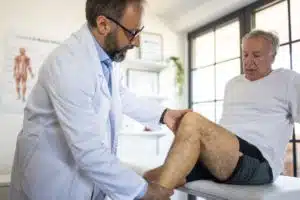 Doctor examining a patient's knee at doctor's clinic to see if he is a good candidate for arthroscopic knee surgery.
