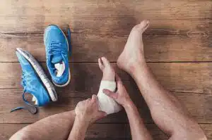 Unrecognizable injured runner sitting on a wooden floor background