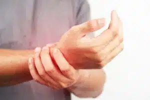 Asian male arms holding his painful wrist caused by exercise. Asian man hand holding his pain wrist isolated on background
