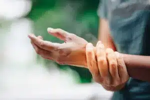 A close-up image of a young woman showing signs of joint pain in her wrist.